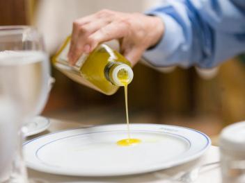 Un hombre echa aceite a su plato en un restaurante