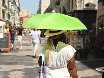 Una mujer se protege con una sombrilla del calor extremo en Niza en mitad de julio
