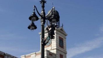 Un activista se encarama a una farola de la Puerta del Sol para protestar contra Madrid 2020