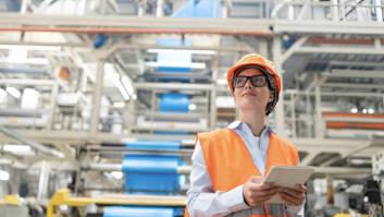 Una ingeniera que viste un chaleco y un casco de color naranja brillante