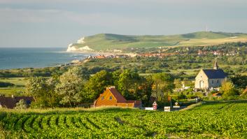 Vista de una zona agrícola en el norte de Francia, con cultivos, viviendas rurales y la costa al fondo en un día despejado.