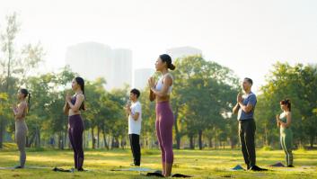 Varias personas haciendo yoga en un parque, en una imagen de archivo