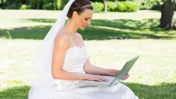 Una novia usando una computadora portátil mientras está sentada en el césped del jardín