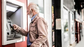 Un hombre mayor insertando una tarjeta de crédito en cajero automático