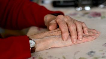 Las manos de una señora mayor apoyadas sobre una mesa