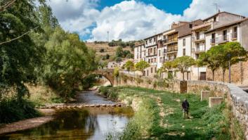 Covarrubias, Burgos Province, Castilla y León, España, September 18, 2021: Outside the walls, man with dog at the walk along the banks of the Arlanza river. Covarrubias, located 40 kilometers southeast of Burgos, is undoubtedly one of the most beautiful towns in Spain. Covarrubias is now a town that stands out above all for its traditional architecture built with wooden and adobe structures. White facades and wooden frames, well cared for, which form a set of great beauty.