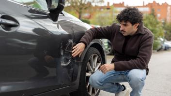 Un conductor mira un rasguño de su coche