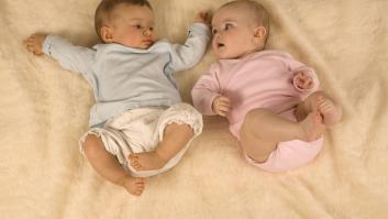 Un bebé vestido de azul y otro de color rosa