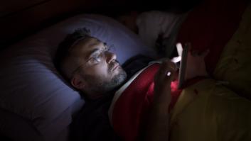 Un hombre usando el móvil en la cama antes de dormir