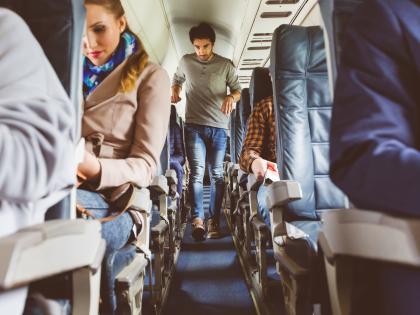 Passengers on seat during flight with man walking in aisle. Interior of airplane with people sitting on seats. People traveling by plane.

izusek (GETTY IMAGES)
