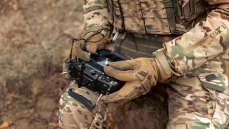 Un militar sentado, manipulando un control de dron.