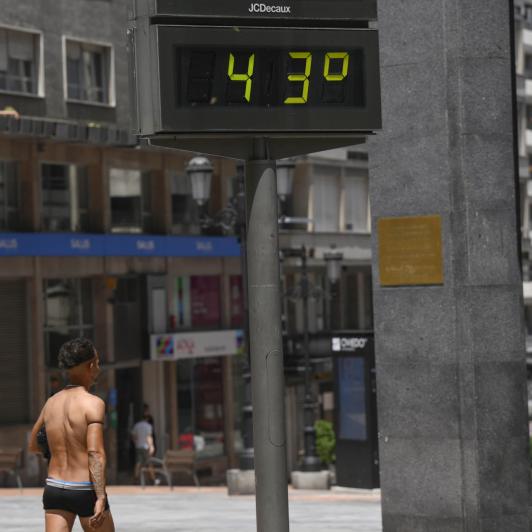 Un hombre semidesnudo pasea por el centro de Oviedo, en plena ola de calor.
