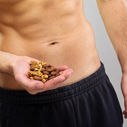 Un hombre musculado con un puñado de frutos secos
