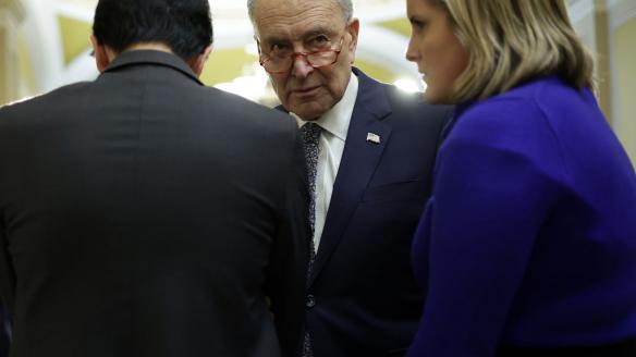 El líder demócrata en el Senado, Chuck Schumer (centro), conversa con varios senadores en los pasillos.