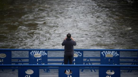 Una persona fotografía el curso del río de Manzanares, crecido por las intensas lluvia que trae la borrasca Martinho.