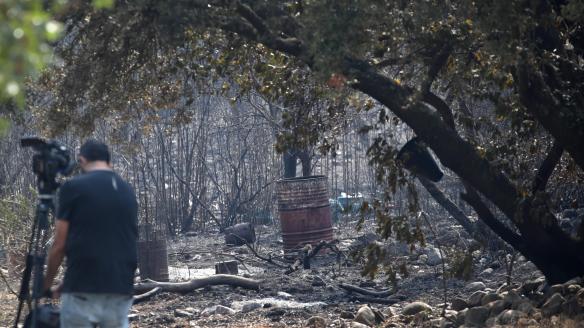 Un reportero toma imágenes tras el paso del incendio en Carucedo (León) este lunes 11 de agosto de 2025.