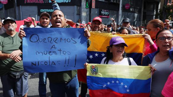 Simpatizantes del oficialismo sostienen carteles en inmediaciones del Palacio de Miraflores este sábado, en Caracas (Venezuela). Chavistas salieron a las calles del centro de Caracas para exigir que "devuelvan" al mandatario venezolano, Nicolás Maduro, luego de que el líder estadounidense, Donald Trump, anunciara la captura del gobernante suramericano en medio de un ataque con misiles durante la madrugada de hoy contra la capital venezolana y otras zonas del país.