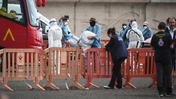 Los pasajeros evacuados este domingo por la tarde del crucero MV Hondius en el puerto de Granadilla de Abona (Tenerife) se dirigen con sus pertenencias personales al autobús de la Unidad Militar de Emergencias