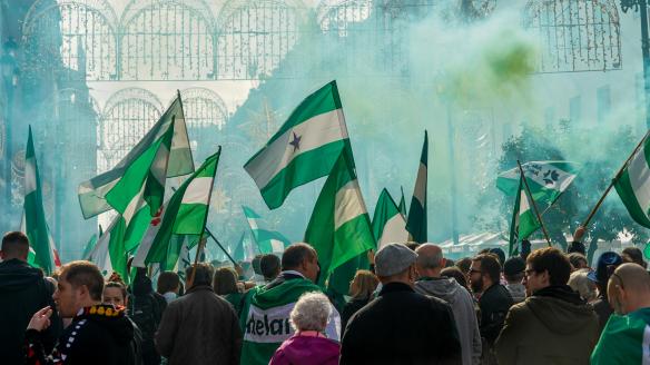 Cientos de personas en una manifestación andalucista en Sevilla en 2022: el ambiente es verde porque se han encendido bengalas y varias personas llevan banderas andaluzas