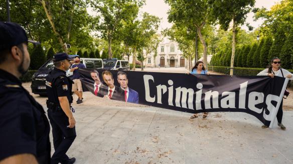 Varias personas despliegan una pancarta en la puerta de la Audiencia Nacional contra Zapatero