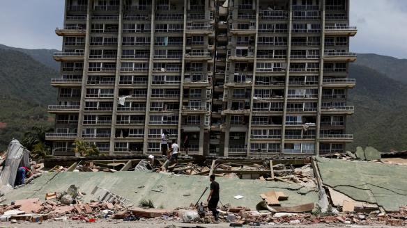 Un grupo de personas inspeccionan los escombros de un edificio dañado tras los terremotos que azotaron el país, en La Guaira (Venezuela), el 25 de junio de 2026.