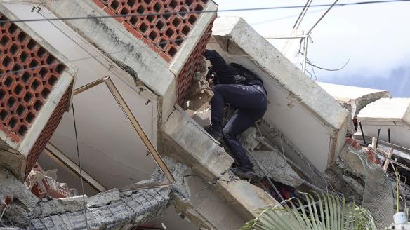 Un rescatista busca entre los escombros de un edificio en La Guaira