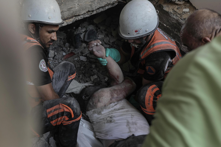 Personal de emergencias y voluntarios gazatíes buscan víctimas entre los escombros de los edificios que han sido bombardeados por el Ejército de Israel.