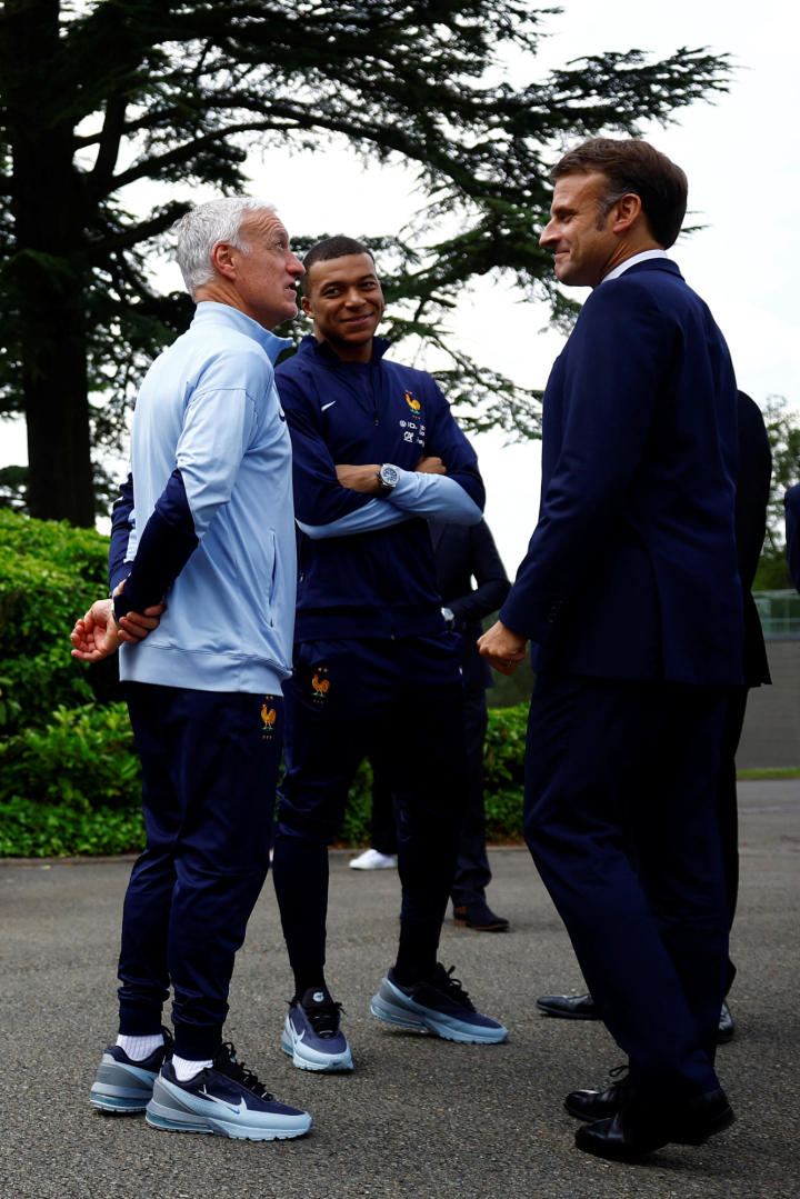 El presidente francés Emmanuel Macron conversando con el seleccionador galo Didier Deschamps, y el delantero Kylian Mbappé.