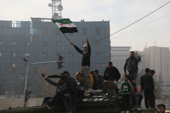 Un grupo de personas celebra la ocupación rebelde en Damasco (Siria).