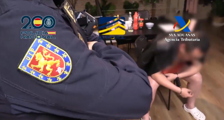 Uno de los agentes custodia a uno de los detenidos durante uno de los registros practicado.