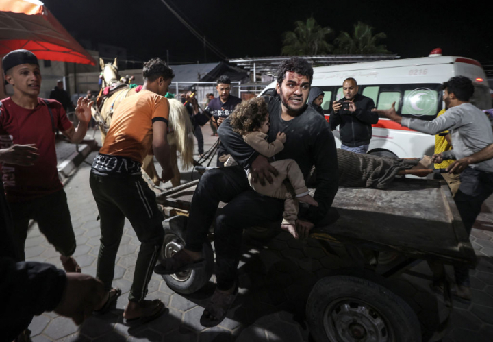 Un hombre llega, con un niño herido en brazos, a un hospital de Gaza después de los bombardeos.