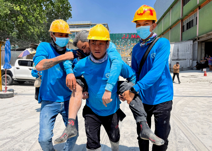 alt="alt="Las autoridades trasladan a un herido a un lugar seguro tras el derrumbamiento de un edificio en Myanmar.""