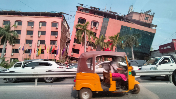 alt="alt="Un motorista circula a los pies de un edificio dañado en Myanmar.""