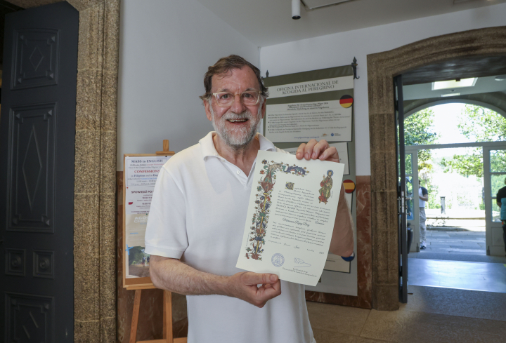 Con un gran gorro, polo blanco y bermudas, el expresidente del Gobierno Mariano Rajoy ha llegado este martes a la plaza del Obradoiro de Santiago de Compostela. En la imagen, recibiendo y mostrando la compostelana.
