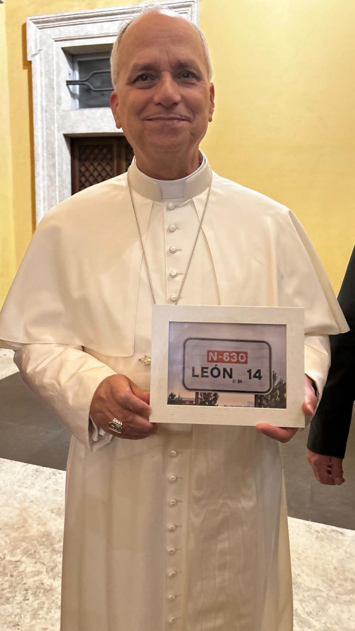 El papa León XIV posa con la señal de 14 kilómetros a León.