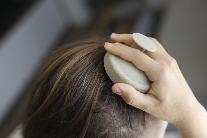 Una mujer masajeando el cuero cabelludo