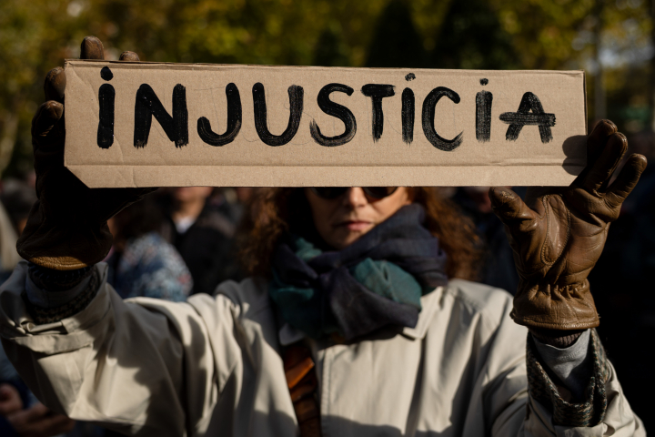 alt="alt="Una mujer lleva un cartel donde se puede leer 'injusticia' en Madrid""