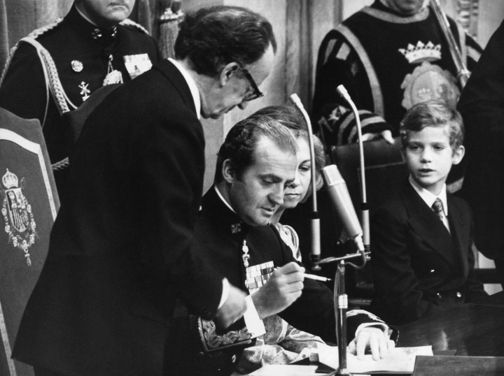 El rey Juan Carlos firmando la Constitución de 1978 en el Congreso en presencia de la reina Sofía y el príncipe Felipe
