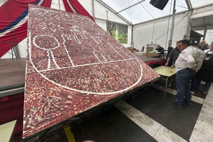 Cumbres Mayores, un pueblo de la sierra de Huelva de algo más de 1.700 habitantes, ha vuelto a servir este sábado el plato de jamón ibérico de bellota más grande del mundo, conformado por lascas de 25 jamones colocadas sobre una superficie de 15 metros cuadrados. Lo ha hecho en el marco de la XIV Feria Gastronómica y Cultural 'Saborea Cumbres' que, organizada por el ayuntamiento de la localidad, se desarrolla desde el pasado viernes y hasta mañana, e incluye, además, presentaciones artísticas, música en vivo, talleres y exhibiciones culturales. EFE/ Femín Cabanillas