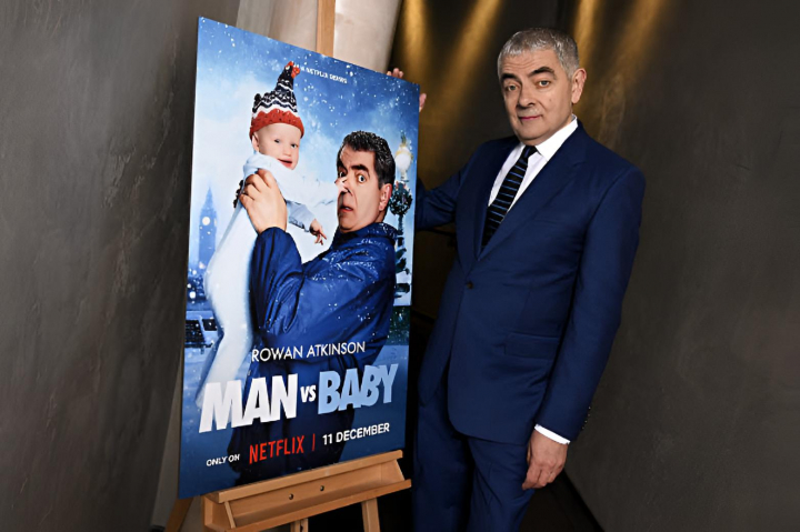 alt="alt="Rowan Atkinson posando junto al cartel de su última serie 'Man Vs Baby'""