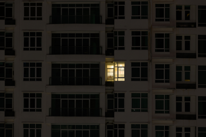Imagen de archivo de la fachada de un edificio con solo una vivienda con la luz encendida.
