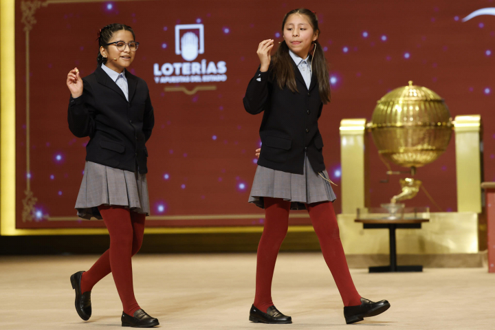 Alba Yadira Machaca (d) e Italy Andrea Blanco cantan el 79432, agraciado con el premio gordo del Sorteo de la Lotería de Navidad