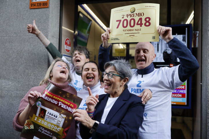 Varias personas celebran a las puertas de la administración de loterías 16, del número 10 de la calle Barquillo, en el madrileño barrio de Chueca, donde se ha vendido íntegramente el 70.048, el segundo premio del Sorteo Extraordinario de la Lotería de Navidad.