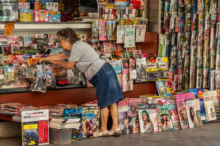 Una mujer ordena revistas y periódicos en un quiosco de prensa en Madrid.