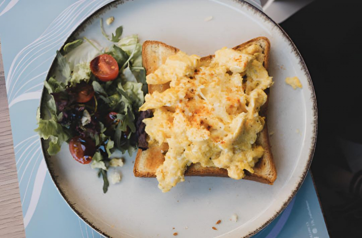 alt="alt="Una rebanada de pan con huevos revueltos y varios vegetales de guarnición""