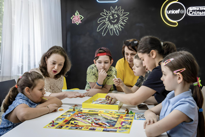 Voluntarios de UNICEF juegan a un juego de mesa con niños en un centro de voluntariado