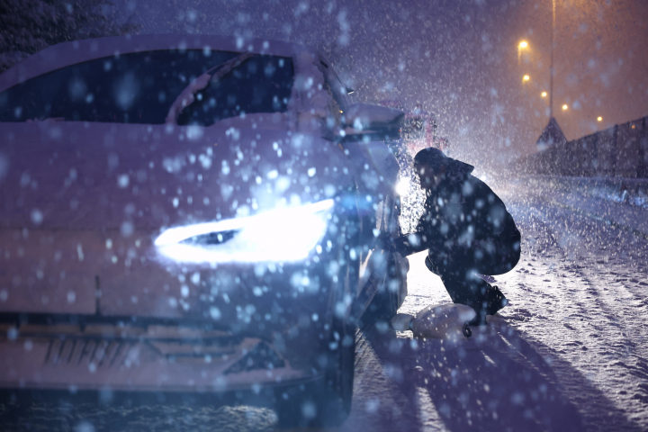 Un hombre coloca las fundas de nieve antideslizantes durante una nevada a primera hora en Torrelodones, Madrid este miércoles.