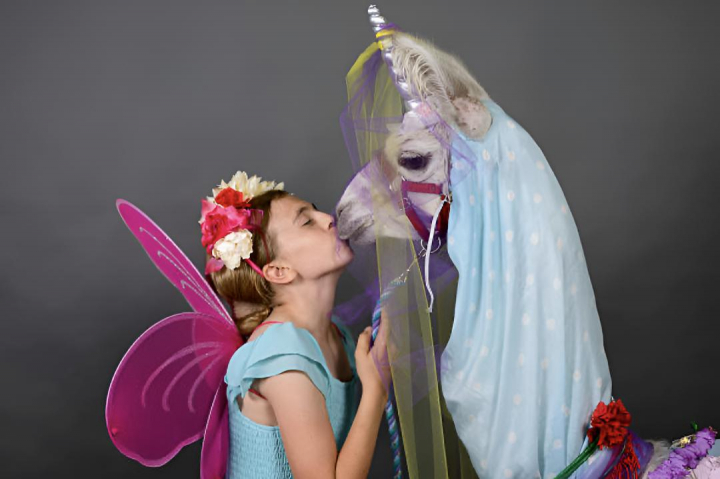 alt="alt="Una niña dando un beso a un caballo vestido de unicornio""