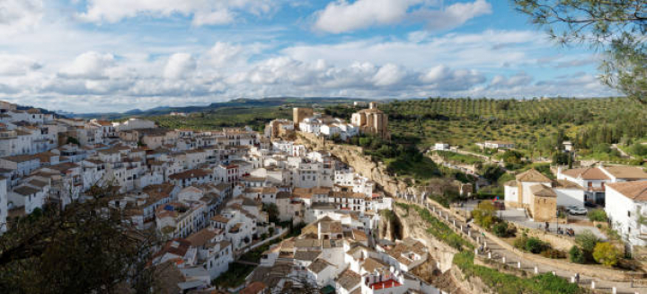 alt="alt="The white village of Setenil de las bodegas, located in the northern part of Cádiz, Andalusia. This picturesque town is located on a hill, where its main church is prominently seen. Image taken on a clear spring afternoon""