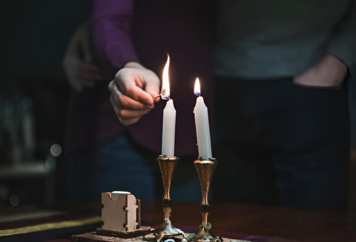 Una persona encendiendo dos velas con una cerilla
